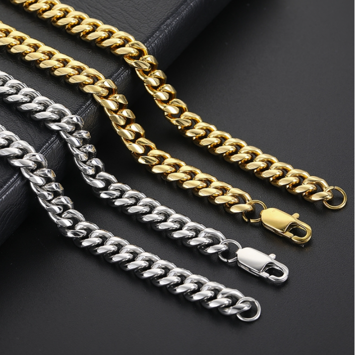 Three curb chain necklaces in gold and silver, arranged diagonally on a black leather surface.