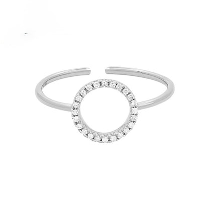 A silver-toned open cuff ring featuring a central circular motif paved with small clear stones, shown on a plain white background.