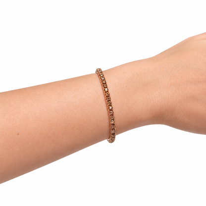 rose gold tennis bracelet with small champagne stone, worn woman's wrist in white background
